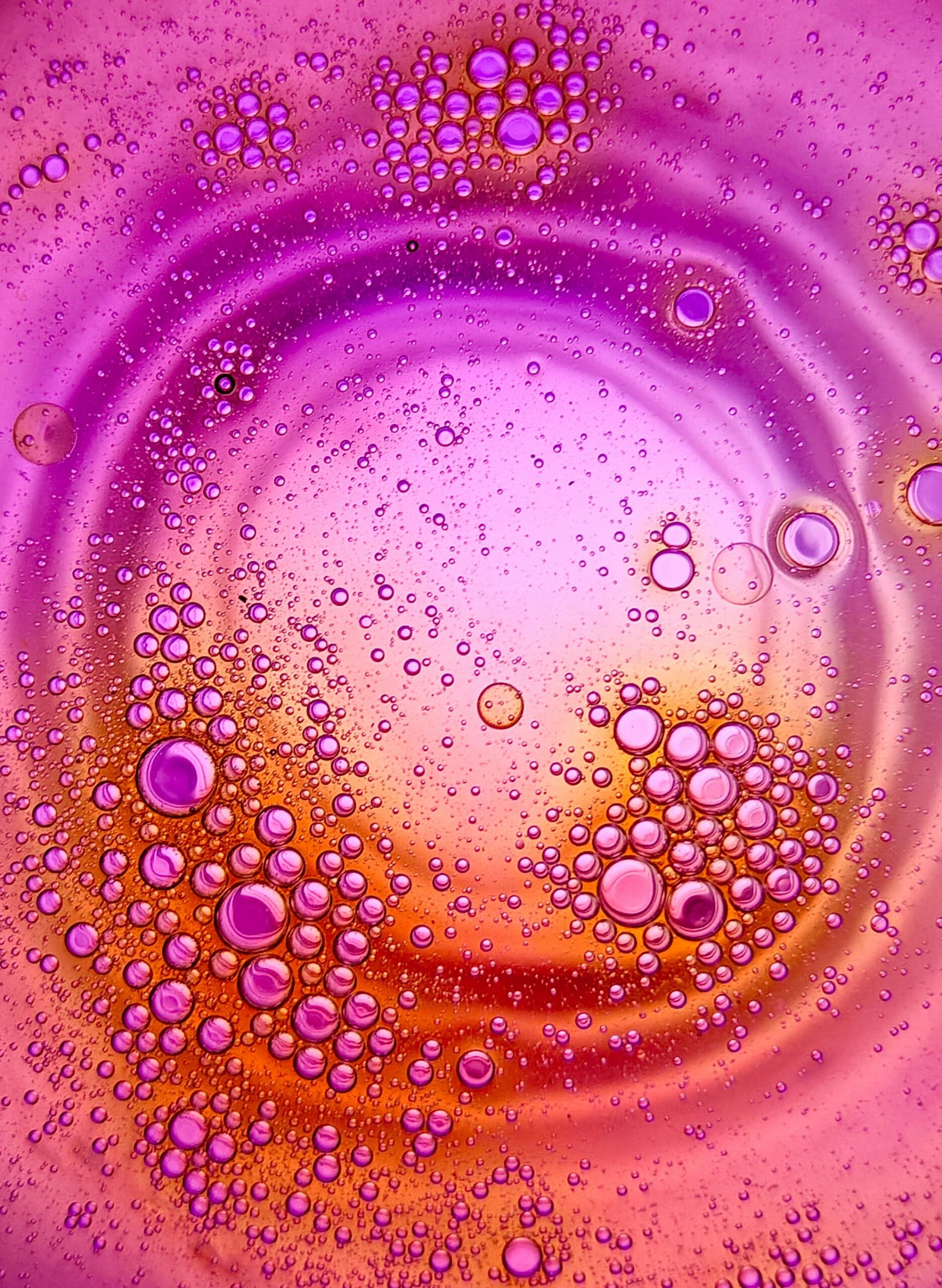Abstract oil bubbles in water creating a vibrant purple and orange artistic pattern.
